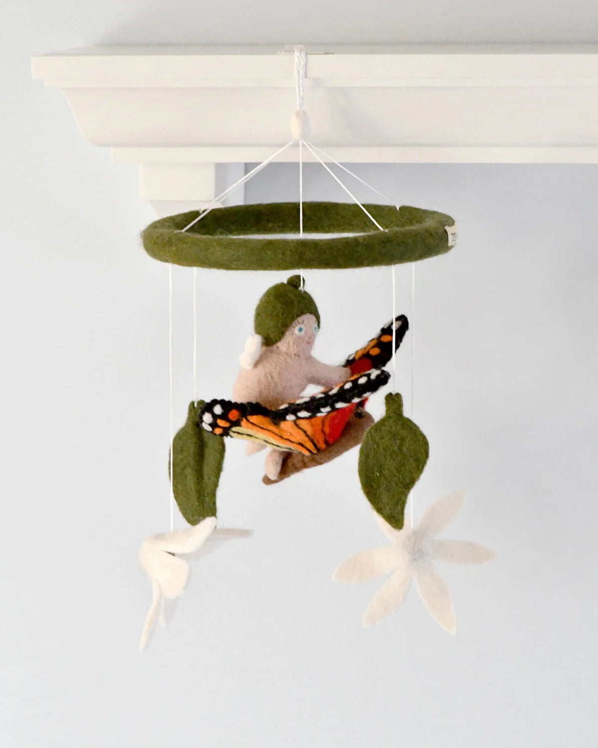 Felt mobile with a child, butterfly, and leaves on a white background